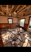 Room before renovation — gutted interior with exposed framing and debris